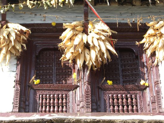 Kunstvoll geschnitzte Fenster und Mais unter dem Dach zum Trocknen