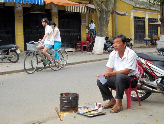Dieser Mann opfert gerade Seidenpapier und Papiergeld für seine Ahnen. Während Tet ein überall zu beobachtendes Bild.
