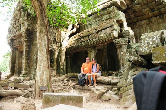 Wir sitzen auf einer Riesenbaumwurzel im Ta Prohm