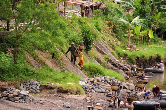 Am Fluss, per Hand werden Sand, Kies und große Steine gefördert