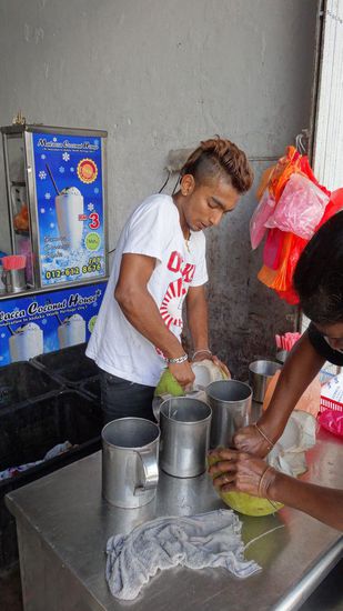 Sie schaben das Mark aus den frischen Kokosnüssen heraus, um Kokosmilch herzustellen