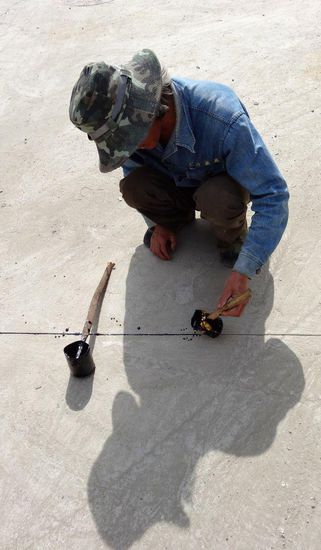 Mit ruhiger Hand wird flüssiger Teer in die Fuge gegossen