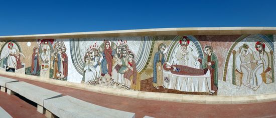 Vor dem Portal grosse im Halbkreis angeordnete Mosaikwände mit christlichen Motiven