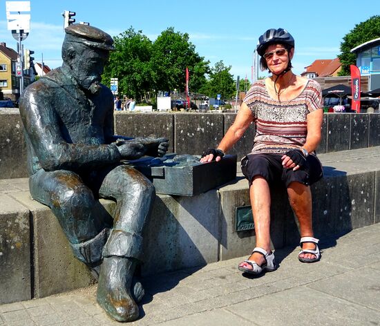 Die Skulptur "Sitzender Fischer" steht seit 2003 an der Uferpromenade direkt an der Brücke. Sie wurde von Jörg Plickat geschaffen und dokumentiert die Fischereitradition des Ortes. Die kleine Heringsbronzetafel ist eine von vielen, die sich überall in den Gehwegspflasterungen befinden. Sie sind mit den Namen von Bürgern versehen, die sich mit Spenden für ein attraktives Stadtbild engagiert haben.