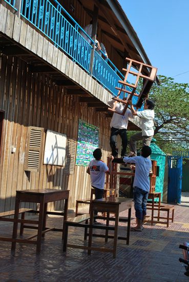 Das Mobiliar des oberen Klassenraums wird heruntergeschafft, um es in das neue Gebaeude zu transportieren. Alle packen selbstverstaendlich mit an.