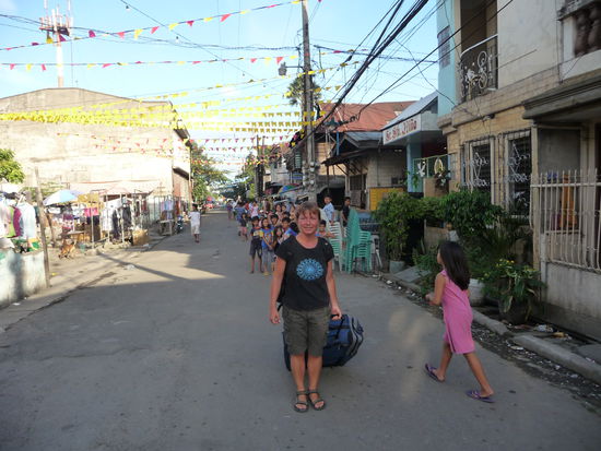 Wir entfernen uns vom Hafen und gehen durch eine Straße, die sich in einem der ärmeren Stadtteile von Cebu befindet. Im Hintergrund sieht man, daß ein paar Kinder neugierig schauen...
