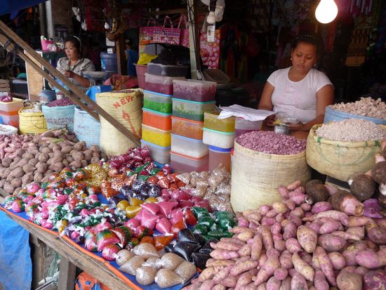 Zwischen den Süßkartoffeln werden Päckchen in den buntesten Farben verkauft. Es handelt sich vermutlich um irgendwelche Samen. Die Verkäuferin sagt, daß sie in Milche gerührt werden.