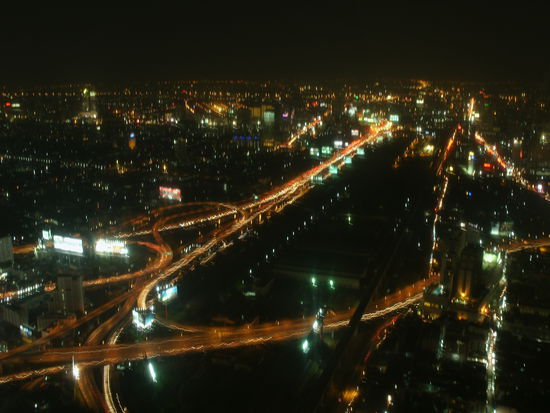 Bangkok bei Nacht aus dem 87. Stock des hoechsten Hotels der Stadt. Die Plattform ganz oben dreht sich um das gesamte Gebaeude. Ganz schoen hoch sag ich Euch!