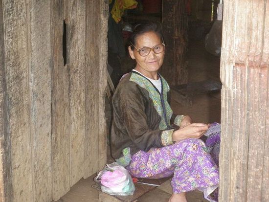 Eine Hmong-Frau lädt uns zu sich nach Hause ein. Sie hat noch einen Zahn aber strahlt über das ganze Gesicht und hat Freude an unserem Besuch. Ihr Mann ist im Dschungel wohl am illegalen jagen...