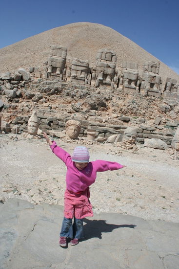 Mia fliegt fast davon. Im Hintergrund der Tumulus, die riesigen Steinkörper und dann die runtergefallenen wieder aufgestellte Köpfe dazu.