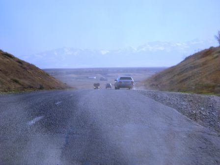Die Strassen in Kasachstan sind nicht so schlecht wie in Turkmenistan oder Usbekistan, einfach ein wenig holperig. Nach diesem Hügelchen sahen wir - im Hintergrund - die schneebedeckten Berge und wussten: Ab jetzt wirds nur noch kälter und die Heizung in unserem Nissan Patrol wird eingeschaltet.