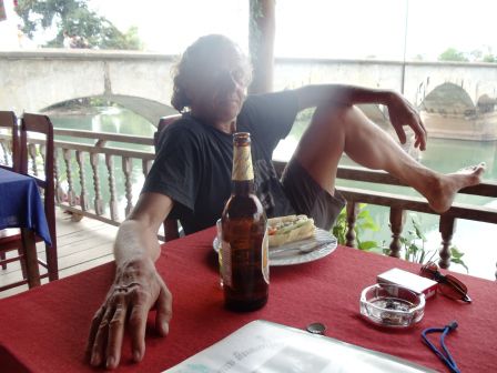 Hier warten wir entspannt am Mekong auf unser Boot für die Rückfahrt. Im Hintergrund die Französische Brücke von Don Khon nach Don Det.