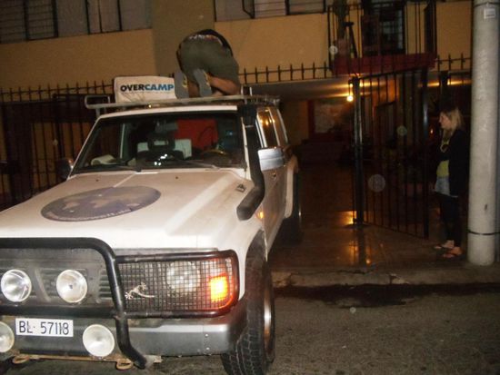 Demontage des Dachzeltes und der Winterräder vor der Wohnung von Valentino mit Allister auf dem Dach und von Sarah beobachtet