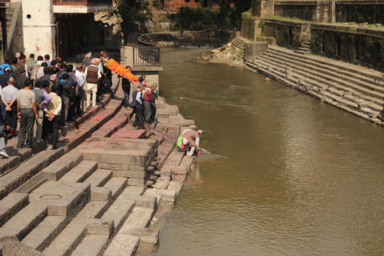 Vor der Verbrennung werden die Fuesse der Leiche in den hl. Bagmati eingetaucht