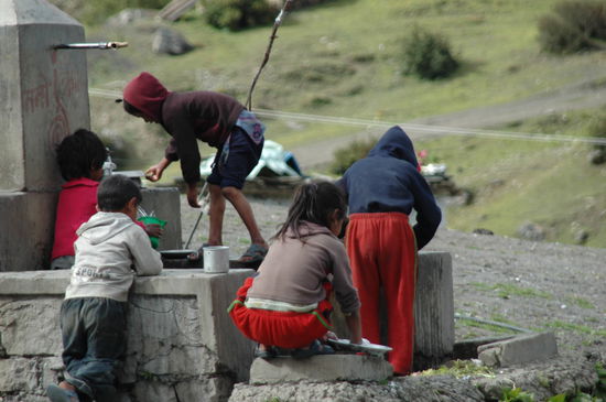 Kinder morgens beim waschen am Dorfbrunnen