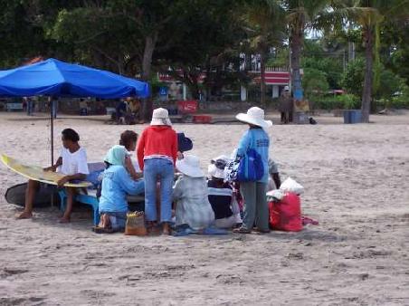 Hier haben 2 Strandbesucher (verdeckt) den Fehler gemacht, etwas zu kaufen, was ihnen die dauerhafte Anhaenglichkeit von 8 fliegenden Verkaeufern garantiert