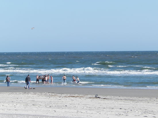 Siegtrunkene euphorische Basketballfans, die sich Anfang März voller Freude in den Atlantik stürzen!