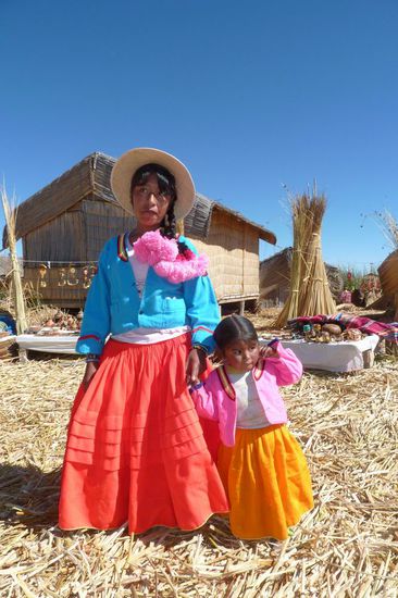 Puno - Schilfinsel - Eine kleine Familie mit Kind. Sie lieben farbenfrohe Kleidung und laufen grundsätzlich Barfuss auf dem Stroh. Ungefähr 8 Familien leben auf einer Insel.