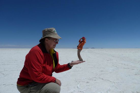 Salar de Uyuni - Dieses Witzbild hat unser liebenswerter Guide Illy gemacht. Er musste sich dazu komplett auf den Bauch legen und das war auf der harten Salzkruste nicht einfach. Denn jeder wollte so ein Bild haben. Hier ist Birgit auf meiner Hand.