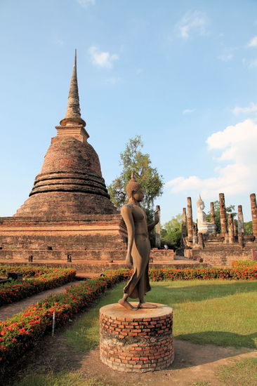 Buddhastatue vor einem großen Chedi.