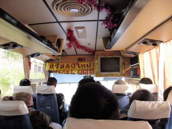 Der Bus von innen. Links vom Gang zwei Sitze und rechts drei Sitze. Die Sitze waren so schmal, dass es selbst für die zierlichen Thailänder eng war. Ich saß stundenlang mit einer Pobacke auf der Kante des Sitzes und versuchte nicht in den Gang zu fallen, da die Strecke teilweise sehr kurvig war. Selbst die Einheimischen mussten sich auf einigen Streckenabschnitten an den Vordersitzen festhalten! Sehr schön war aber die Deko vorne im Bus. Merry Christmas auf thailändisch und englisch, plus schöne Girlanden (da kommt fast weihnachtliche Stimmung auf!).