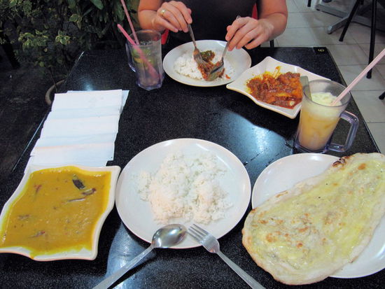 Essen bei unserem Lieblings-Inder. In der Mitte fehlt noch das Roti. Als Nachspeise gab's meist Bananenpfannkuchen. Nach unserem Verständnis waren es aber eher Crepes mit Bananen-Honig-Füllung und dazu wurden zwei herzhafte Soßen gereicht.