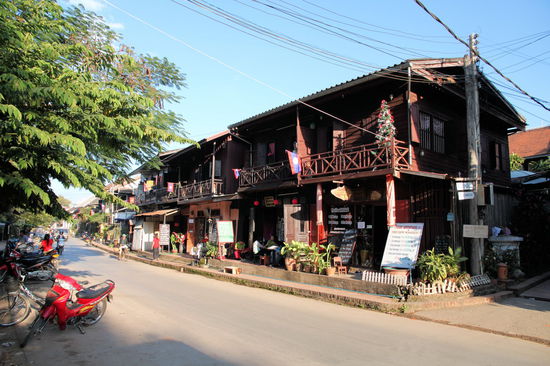 Typische Häuserzeile in Luang Prabang. Im Innenstadtbereich sind (subjektive Einschätzung) zwei Drittel der Häuser bereits fertig saniert und der Großteil der übrigen Häuser wird gerade saniert. Man sieht nur noch sehr wenige unsanierte Häuser. Alle sanierten Häuser werden in irgendeiner Weise touristisch genutzt (Unterkunft, Gastronomie, Geschäft etc.), wodurch immer weniger Häuser (in der Altstadt/Innenstadt) von Einheimischen bewohnt werden.