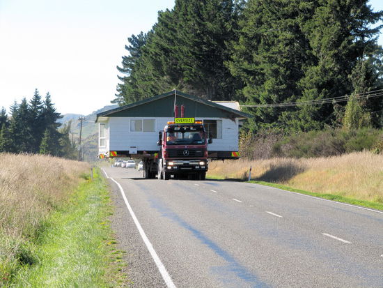 Wir flüchteten uns mit unserem Campervan auf die nächste Schotterfläche am Straßenrand. Ein gute Entscheidung, denn wenige Sekunden später rauschte (mit ca. 60-70 km/h) der Oversize-Transport heran. Ein freihstehendes Einfamilienhaus beim Umzug. 