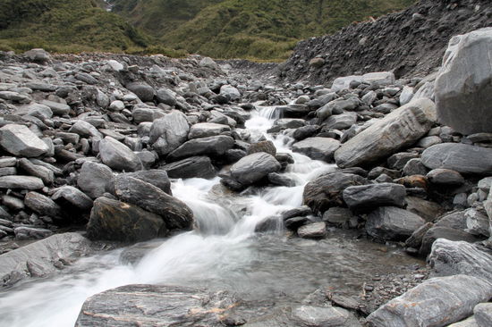 Ein kleiner Bach der seitlich aus den Bergen ins Geröllfeld floss.
