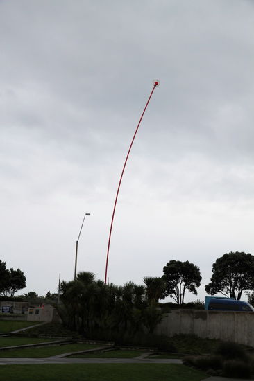 Der lange rote Stab ist der 'Wind Wand' des Künstlers Len Lye. Ein 45 Meter hoher Fiberglasstab, der sich im Wind bis zu 20 Meter verbiegen kann und abends an der Spitze ein rotes Licht hat.