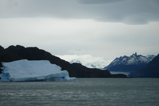Im Vordergrund ein riesiger Eisblock. Im Hintergrund rechts befindet sich weit entfernt ein Gletscher.