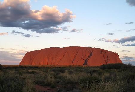 Waehrend des Sonnenuntergangs hat Ayers Rock viele verschiedene Rot/Orange-Toene.
