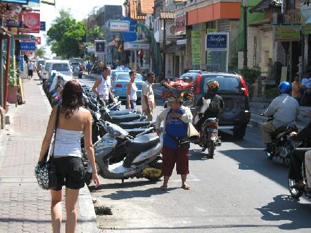 Strassenszene in Kuta, massig Mofas, schwerbeladende Menschen und mittendrin Misses Fu.