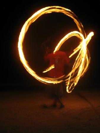 Feuer-Jongleur nachts am Strand