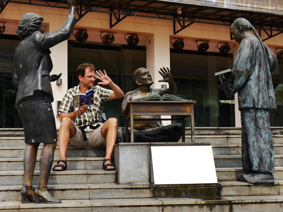 Überall am Ufer stehen Bronzestatuen, die zum Mitmachen einladen.