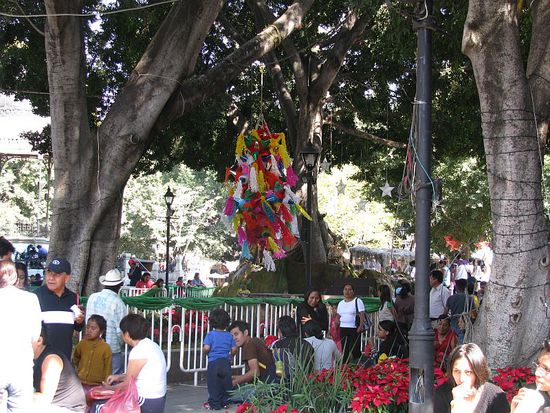 An den Bäumen hängen Pinatas, Pappmachee-Figuren, auf die die Kinder mit Stöcken einschlagen, bis Süßigkeiten herausfallen.