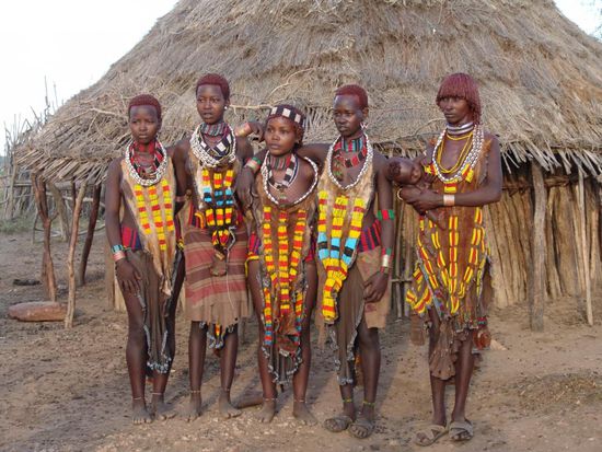 In der Abendsonne besuchen wir noch ein Dorf der Karo. Die Karos sind ein kleines Volk mit vermutlich nur noch etwa 1000 Angehörigen. Ursprünglich Viehzüchter und Bauern an den Ufern des Omos, haben sie durch die Viehseuche Anthrax die Mehrzahl ihrer Tiere verloren, und die Landwirtschaft am Omo-Ufer dominiert den Lebenserwerb. Die Männer formen sich zu besonderen Gelegenheiten, etwa wenn Wildtiere wie Löwen oder Leoparden oder vielleicht auch Feinde getötet wurden, helmartige Kappen aus Ton. Dieser wird auf die Kopfhaut aufgetragen und durch die Haare als "Armierung" an seinem Platz gehalten. Die Tonkappe wird nach dem Trocknen bemalt und mit Kratzmustern geschmückt.