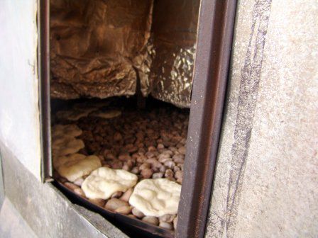 Der Brotteig wird auf eine Drehscheibe mit Steinen geworfen und so gebacken.