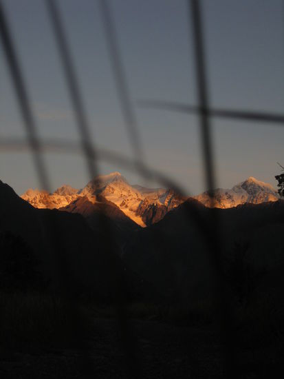 ...wie er von den letzten Sonnenstrahlen des schwindenden Tages hell erleuchtet wird, waehrend die umliegenden Berge bereits in der Abenddaemmerung versunken sind...