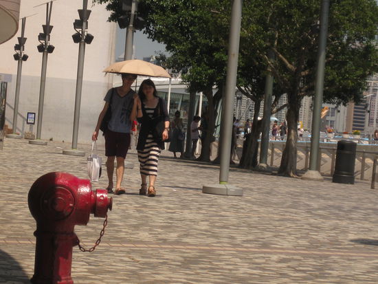 gepflegt flanierende Chinesen bzw. Hongkonesen mit Sonnenschirmchen an der blitzsauberen Hafenpromenade...