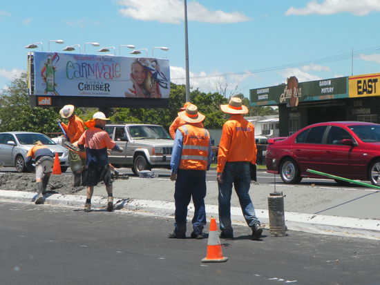dem Klima angepasstes Outfit der Bauarbeiter -  Helm und Sonnenhut kombiniert.