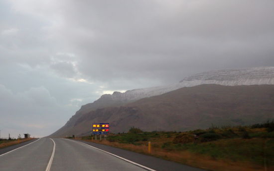 Warntafeln an den Straßen geben Temperatur und Windgeschwindigkeit an, Schnee auf den Bergen