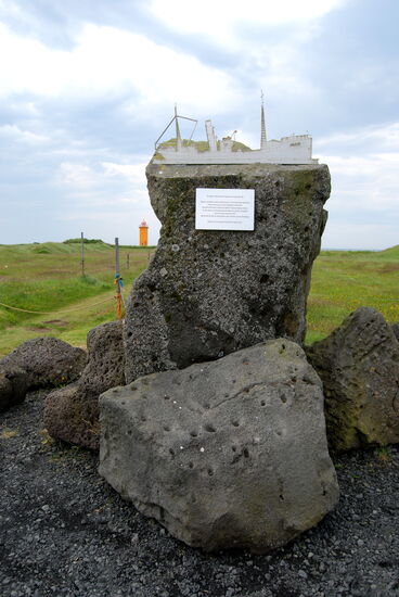 Denkmal für die Opfer des Untergangs eines Fischdampfers mit dem Leuchtturm Stafnes im Hintergrund