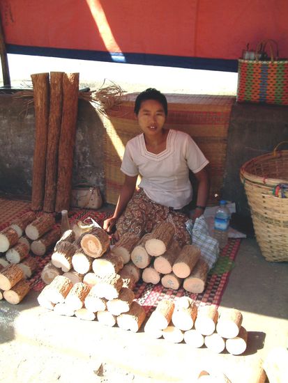 Sie verkauft das Thanakaholz, das sie auf ihre Wangen aufgetragen hat.