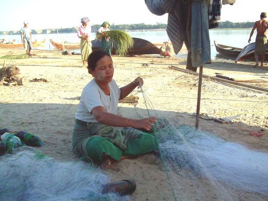 Eine Fischersfrau beim Zusammenlegen des Netzes.