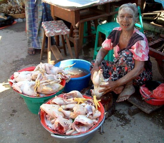Marktfrau mit (ehemals glücklichen) Hühnern.
