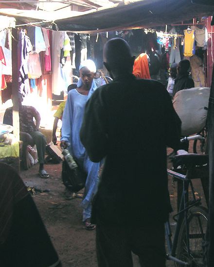 Im Gedränge eines Marktes in Südmali - die Bretterbuden stehen sehr gedrängt aneinander, sodass es fast ein gedeckter Markt wird