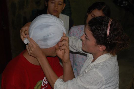 Mimi zeigt wie man einen Kopfverband anlegt.