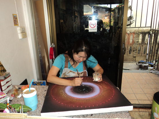 Eine Kuenstlerin bei der Arbeit in Baan Tawai.