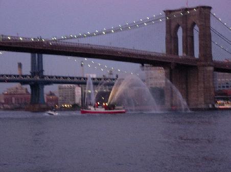 Die Brooklyn Bridge bei Nacht, etwas unscharf, dafuer mit Wasserloescher auf dem Eastriver.